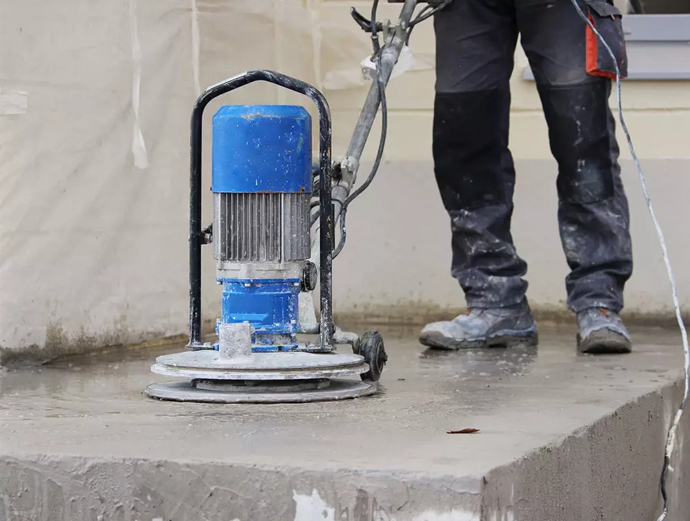 photo of an Edmonton concrete floor company grinding rough concrete surfaces in a commercial warehouse before applying a new concrete surface